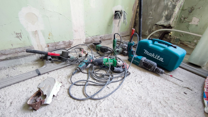 Электроинструменты возле стены с проводкой в процессе ремонта