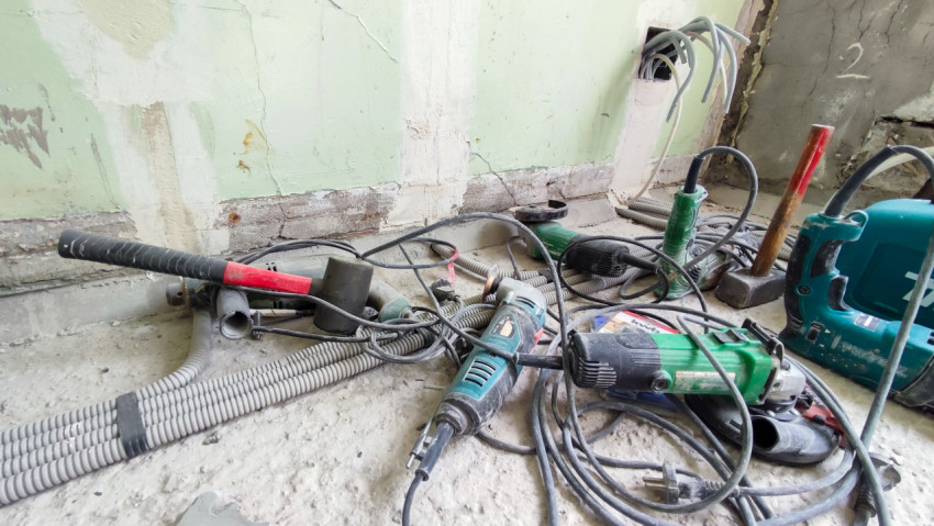 Электроинструменты на полу рядом с монтажной коробкой и гофротрубами
