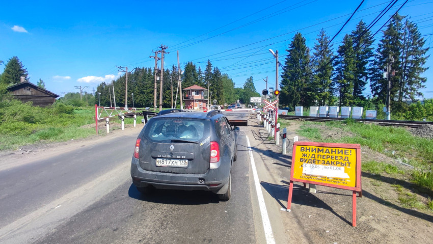 Автомобили у закрытого железнодорожного переезда с предупреждающим щитом