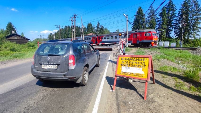 Пригородный поезд проходит через переезд при закрытых шлагбаумах