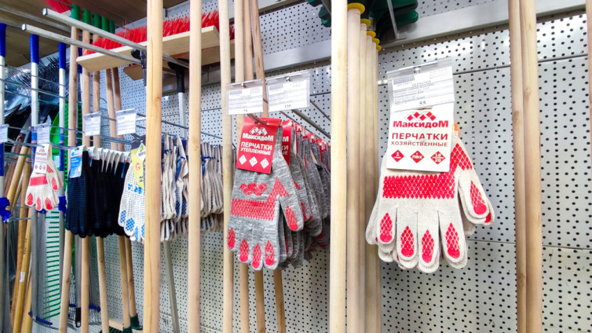 Хозяйственные перчатки и садовый инвентарь на стенде магазина