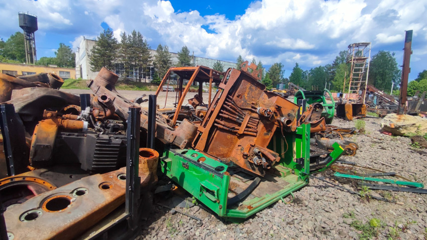 Крупные разобранные блоки техники на щебёночной площадке возле производственных зданий