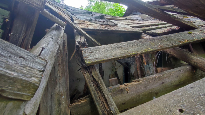 Обрушенные стропила и доски крыши заброшенного строения