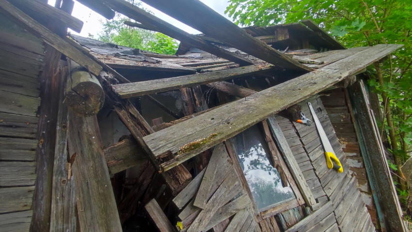 Разрушенная крыша и окно заброшенного деревянного строения