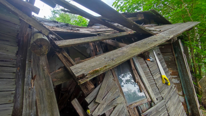 Обрушенные балки над окном заброшенной деревянной постройки