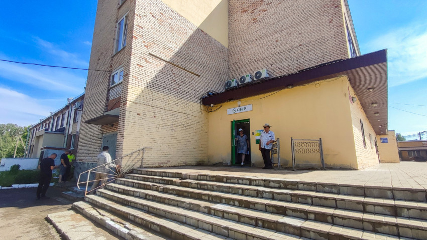 Вход в отделение «Сбер» в кирпичном здании с лестницей и посетителями