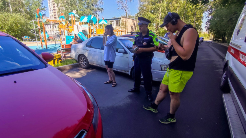 Инспектор ДПС оформляет документы у детской площадки рядом с автомобилем скорой помощи