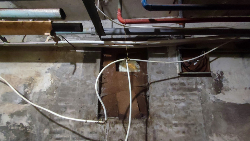 Потолочные трубы и кабели в сыром подвальном техническом коридоре