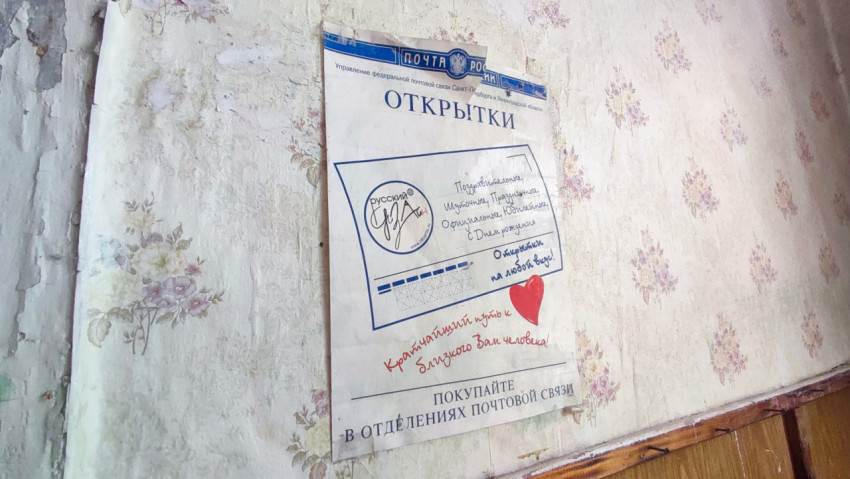 Плакат «Открытки» Почты России на стене с выцветшими обоями