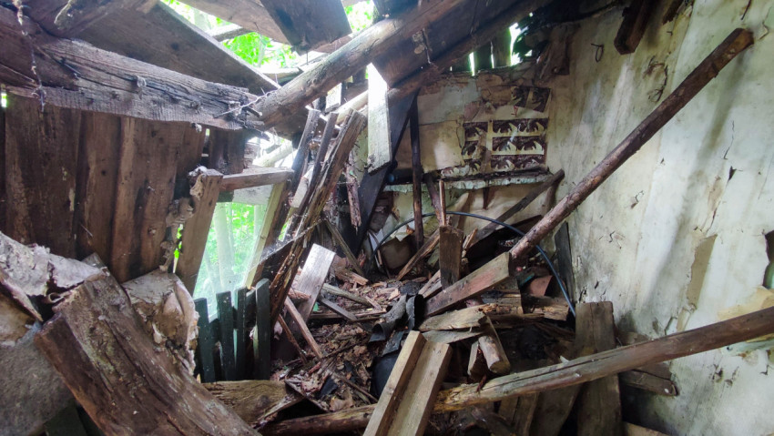 Обрушенный интерьер деревянного дома с разрушенной кровлей