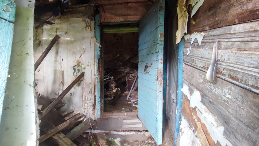 Проход с открытой дверью в заброшенном деревянном доме