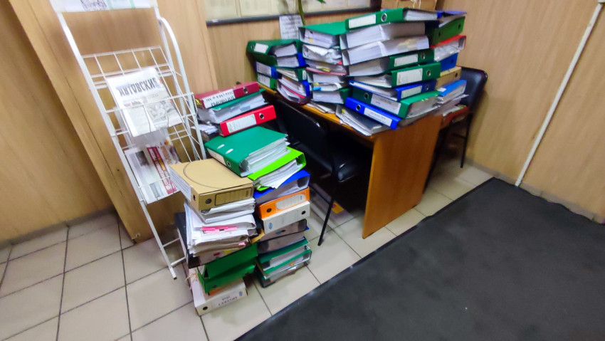 Стопки папок и документов в тесном офисном помещении