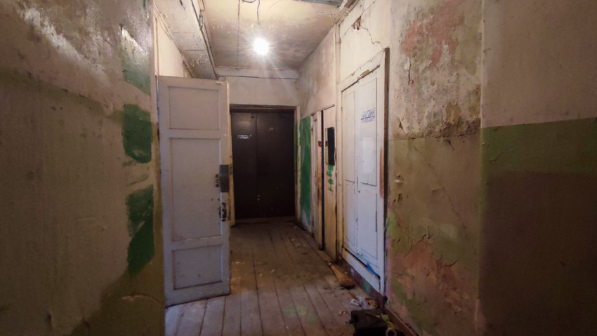 Обшарпанный коридор с белыми дверями и лампочкой под потолком