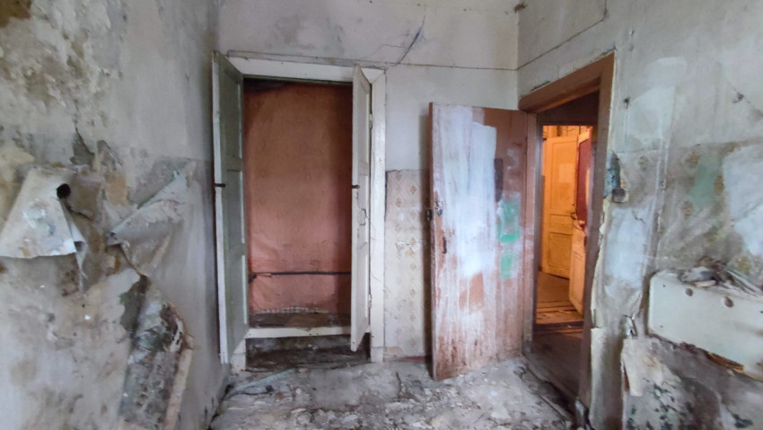 Обшарпанная комната с двумя дверными проёмами и строительным мусором на полу