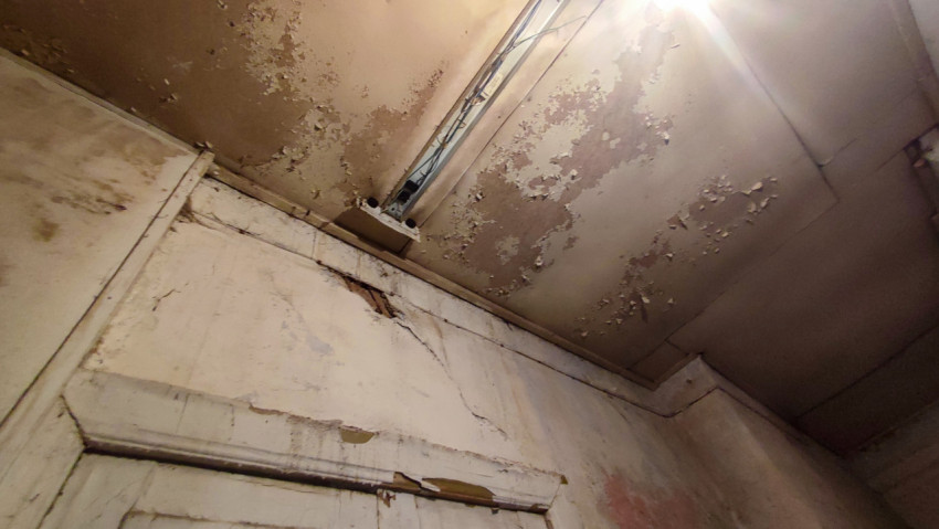 Потолок с люминесцентным светильником и осыпающейся краской над дверным проёмом