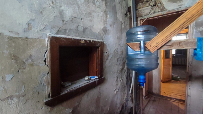 Внутреннее окно с полкой и перевёрнутая бутыль для воды на деревянной конструкции