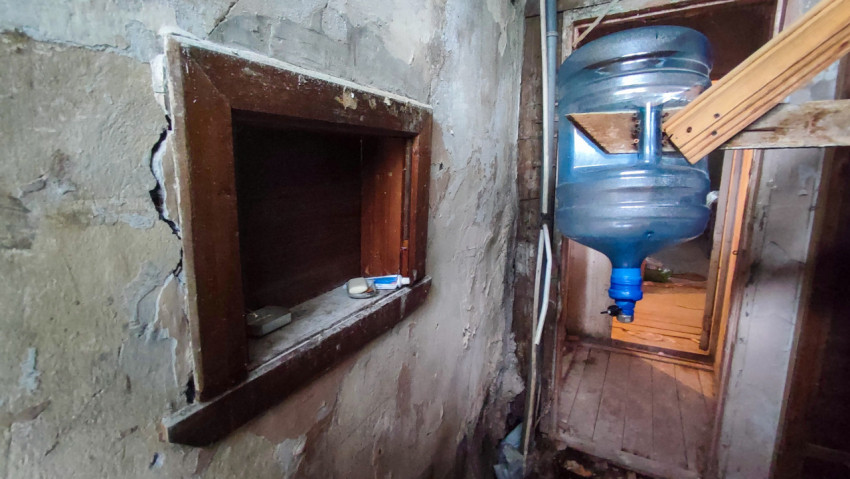 Раздаточное окно в стене с мелкими предметами и подвешенной бутылью для воды