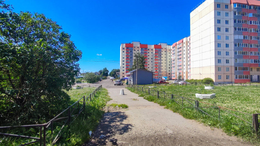 Пешеходная дорожка с ограждениями между пустырем и многоэтажными домами