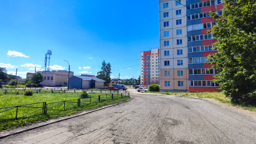 Поворот дворовой дороги у многоэтажного дома и мачты связи на горизонте