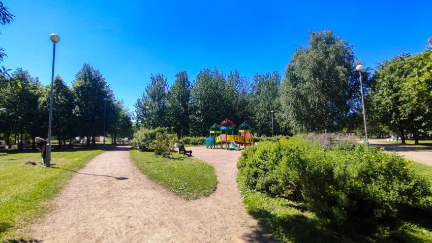 Развилка прогулочных дорожек ведёт к детской площадке среди деревьев в городском парке