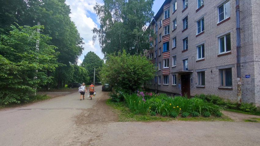 Дворовая улица у кирпичного дома, клумба и прохожие