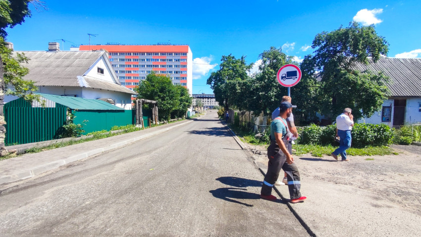 Улица частного сектора с дорожным знаком и пешеходами у обочины