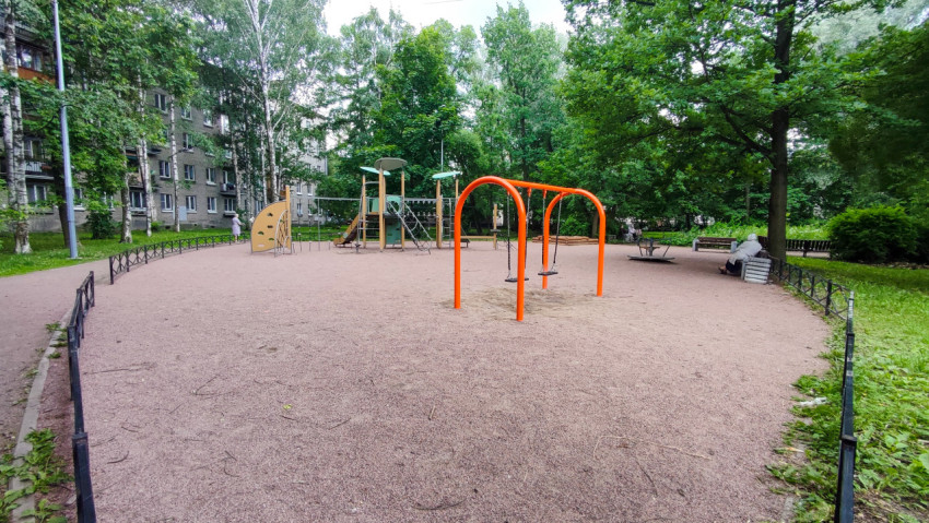 Детская площадка с игровым комплексом и оранжевыми качелями во дворе