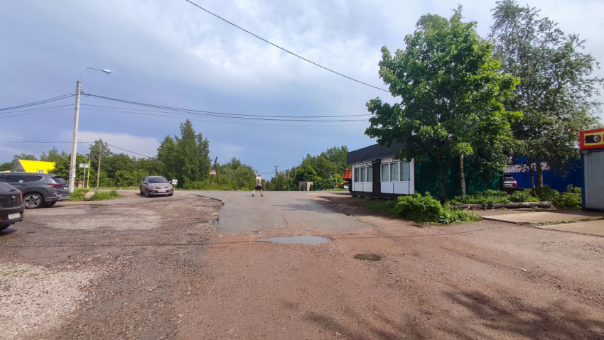 Разбитая дорога с лужами и киоском у развилки