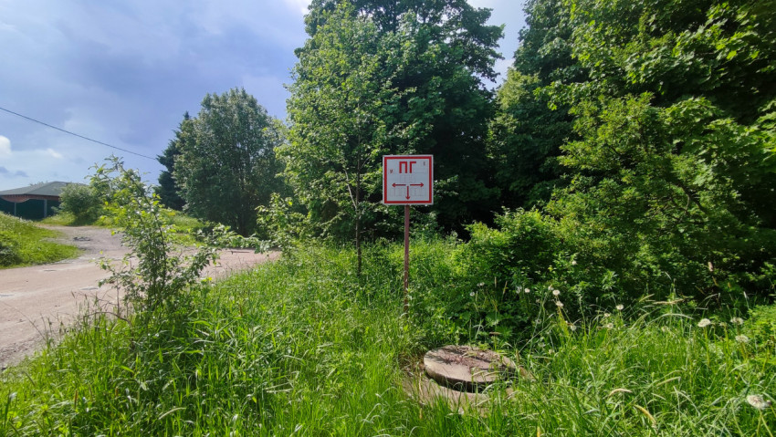 Указатель «ПГ» и люк у поворота сельской дороги