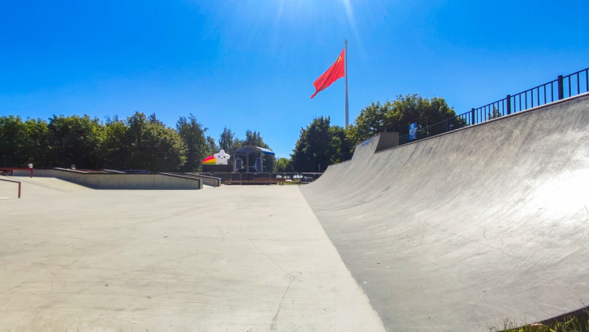 Рампа скейтпарка и красный флаг на флагштоке над площадкой с сценой