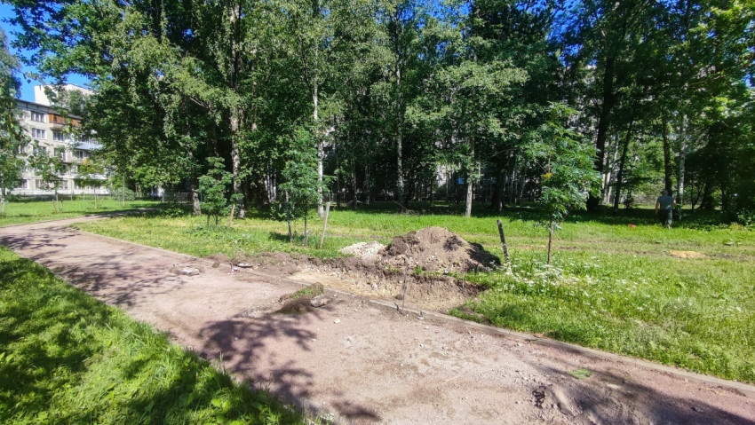 Пешеходная дорожка и кучи грунта в зелёной зоне рядом с жилыми домами