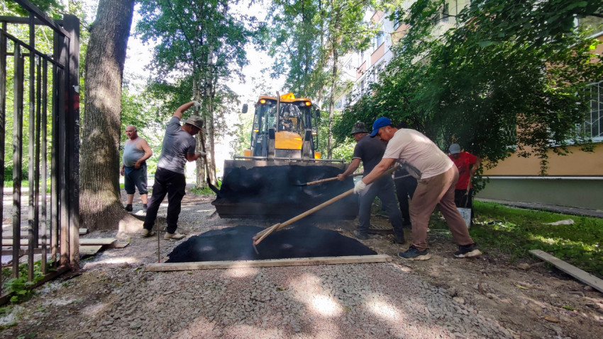 Момент распределения горячего асфальта лопатой и граблями у погрузчика