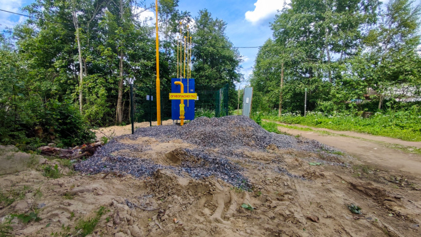 Щебеночная насыпь у газового узла с предупреждающим знаком за ограждением