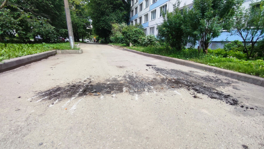 Следы фрезерования и куча асфальтовой крошки на дворовой дороге у жилого дома
