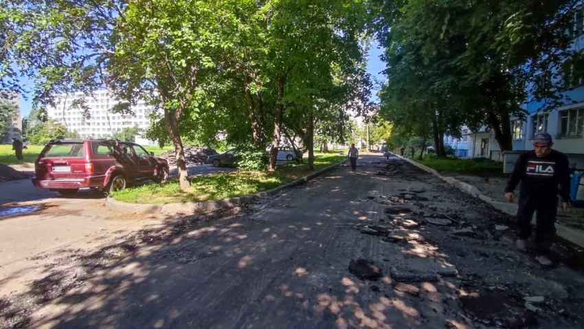 Дворовой проезд после снятия асфальта с крошкой и кусками покрытия под деревьями