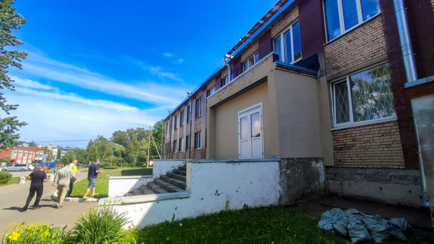 Боковой вход кирпичного здания со ступенями и следами ремонтных работ