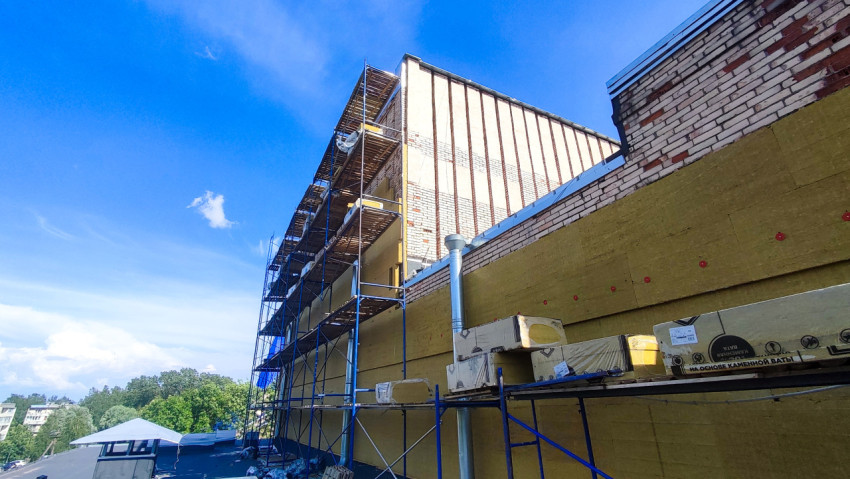 Упаковки утеплителя на настиле лесов возле кирпичного парапета плоской кровли