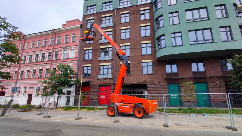 Общий вид улицы с автовышкой AURORA и ограждением зоны работ у жилого дома