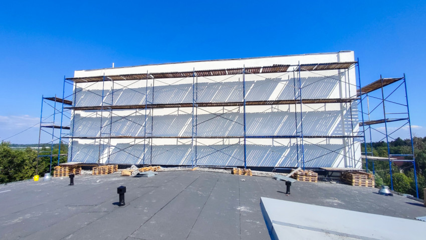 Торцевой фасад здания со строительными лесами, снятый с плоской кровли с вентиляционными стояками и поддонами