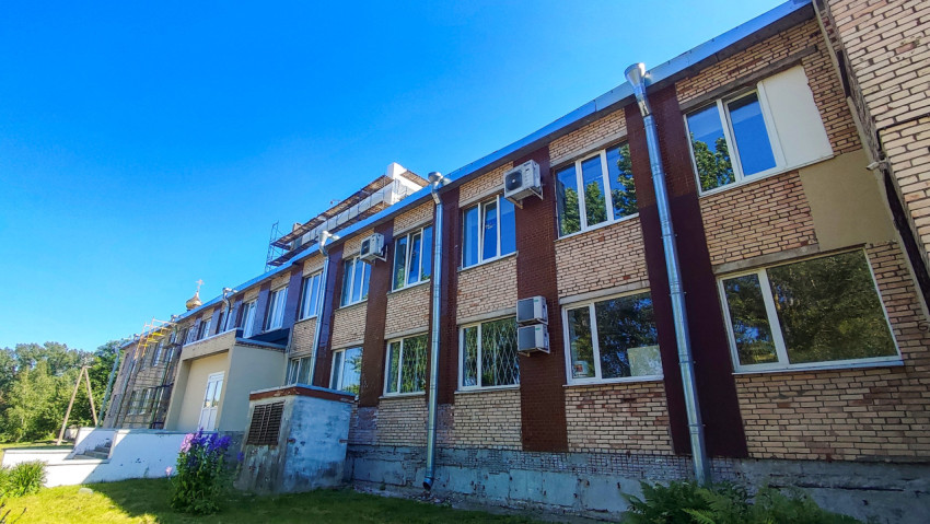 Кирпичный фасад здания с наружными блоками кондиционеров и водосточными трубами в солнечный день