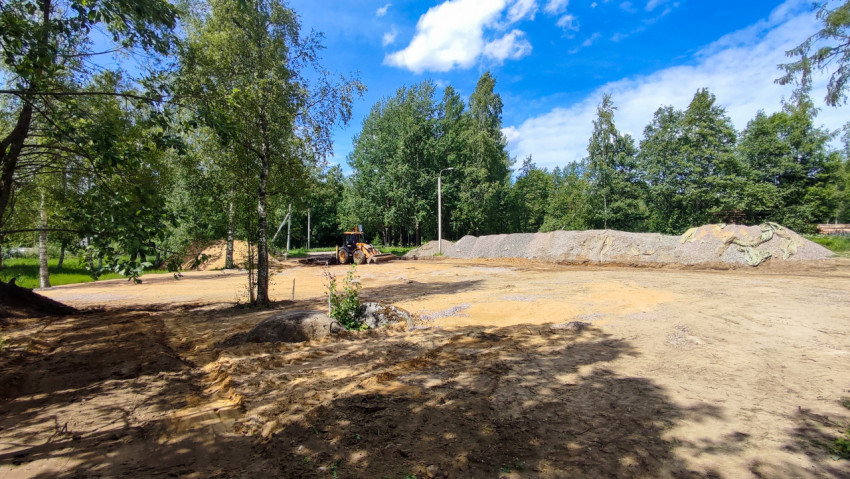 Расчищенная площадка в лесу со спецтехникой и длинными насыпями щебня