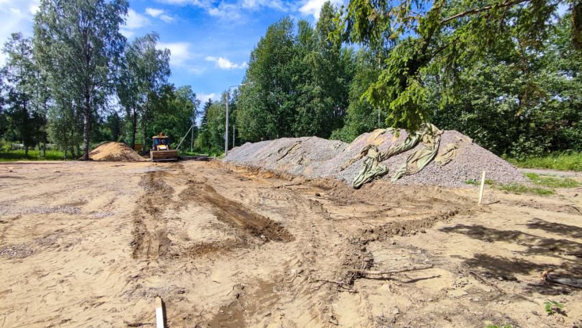 Стройплощадка в лесу с бульдозером и насыпями щебня и песка