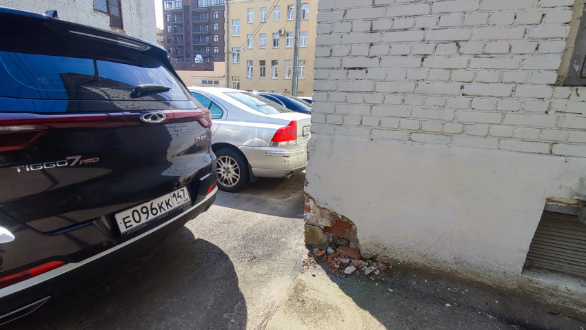 Автомобиль Chery Tiggo 7 Pro у стены с повреждённой штукатуркой в дворовой парковке
