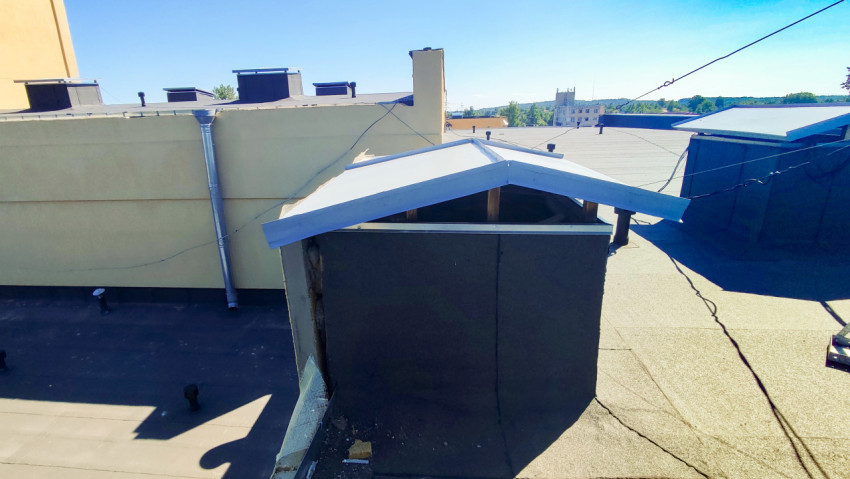 Вентиляционный короб на плоской крыше с металлическим козырьком и проложенными кабелями