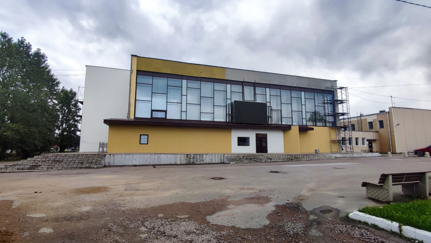 Современное общественное здание со стеклянным фасадом и площадью с поврежденным асфальтом