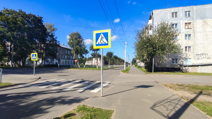 Перекрёсток с пешеходным переходом и дорожными знаками на фоне многоэтажных домов