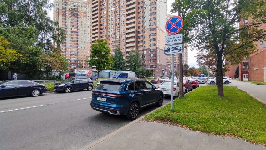 Городская улица с припаркованными автомобилями и дорожным знаком запрета остановки