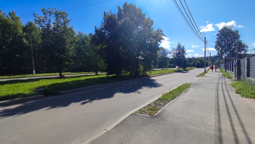 Дорожные знаки пешеходного перехода на городской улице с тротуаром и солнечными бликами