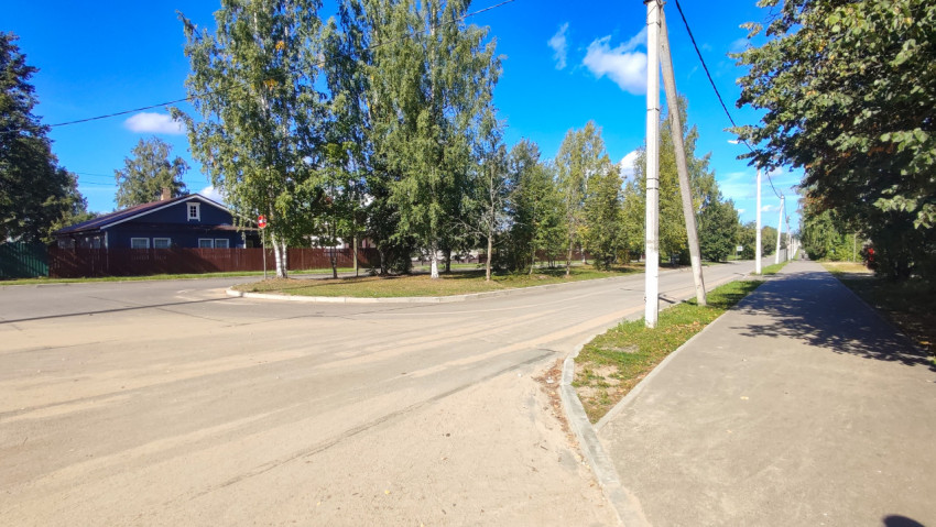 Угол перекрёстка с тротуаром и высыпавшимся песком на асфальте рядом с домом