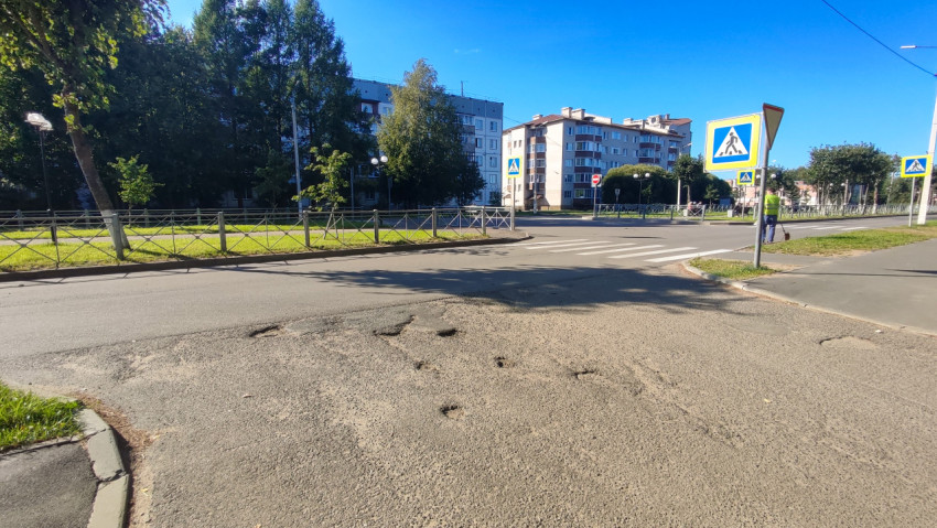 Выбоины и заплатки на асфальте у пешеходного перехода на перекрёстке